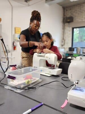 student and teacher sewing
