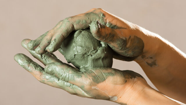 hands of a potter with blue clay